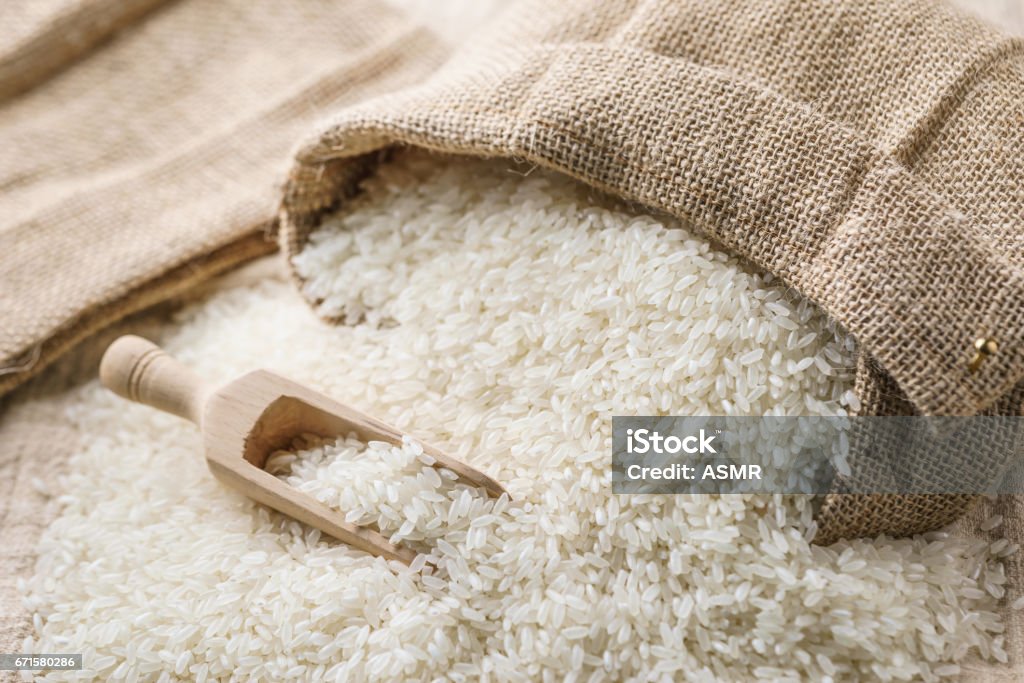 Riz blanc dans un sac en toile avec une pelle en bois